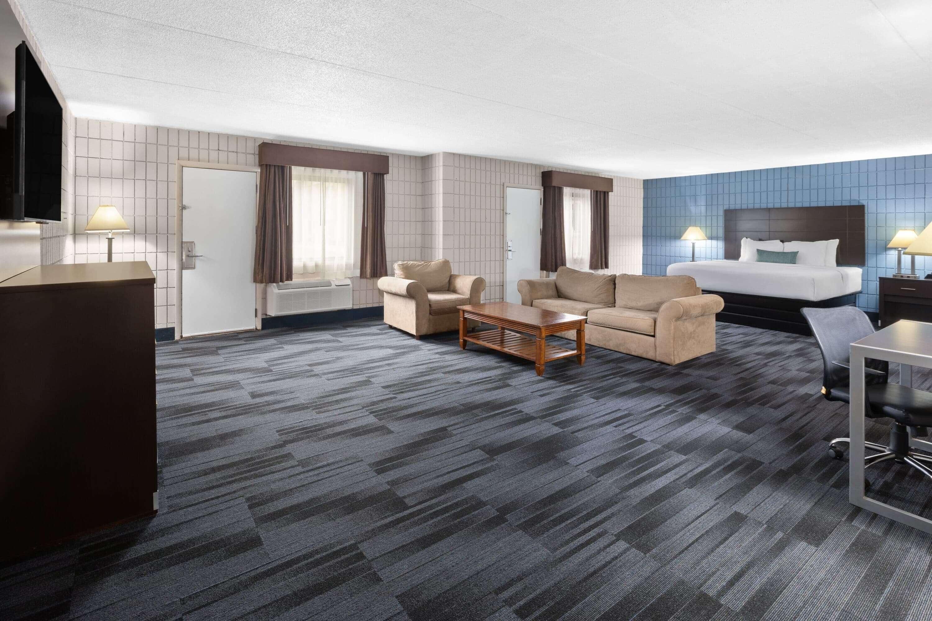 A hotel room with a bed, two sofas, a coffee table, a desk, and a TV.