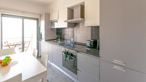 A modern kitchen with a large island, built-in oven, and stainless steel appliances. - Almond Apartment Ocv - Pool & Garage (Albufeira)