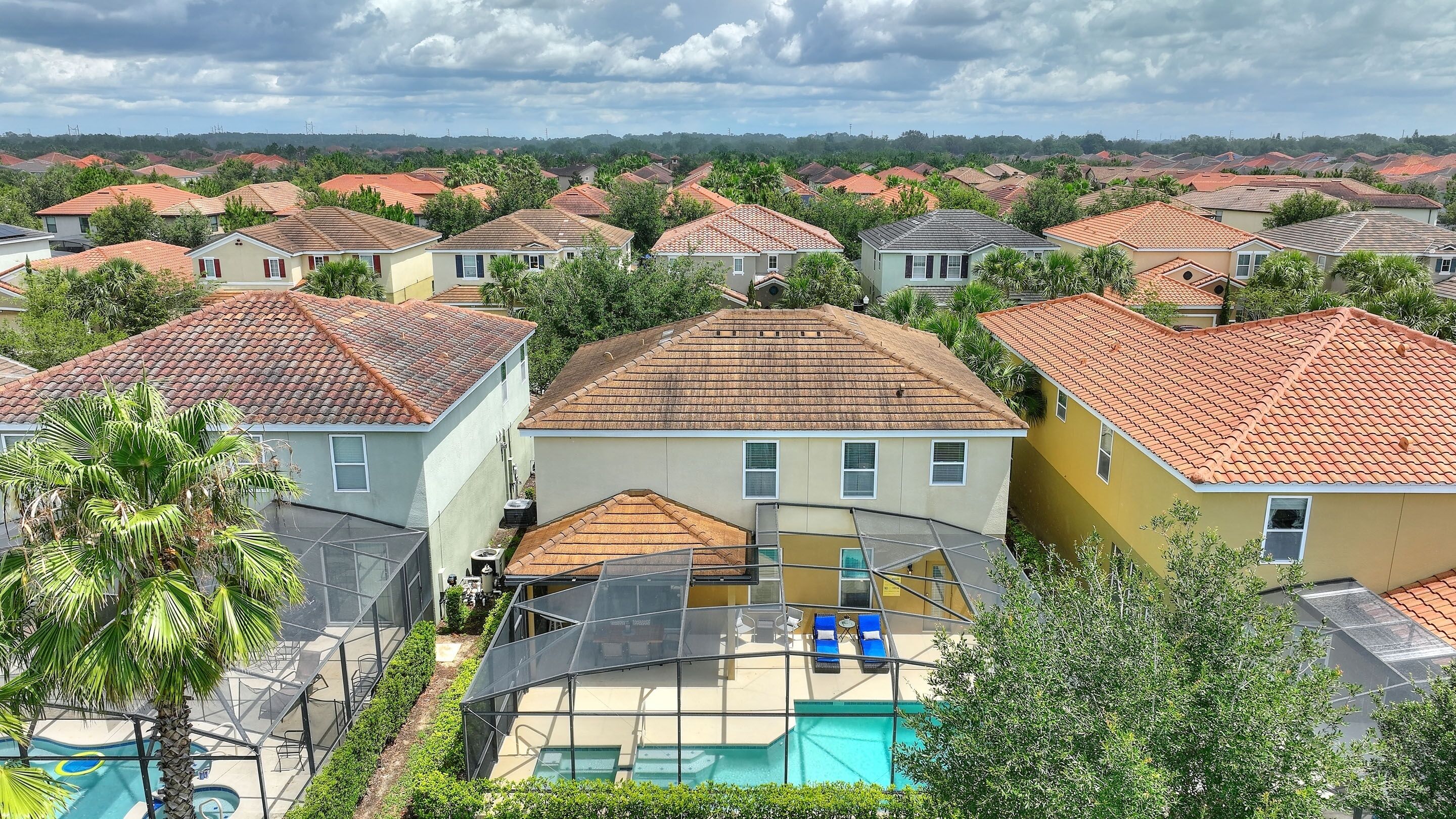 A residential area with houses featuring red-tiled roofs and a swimming pool with sun loungers.