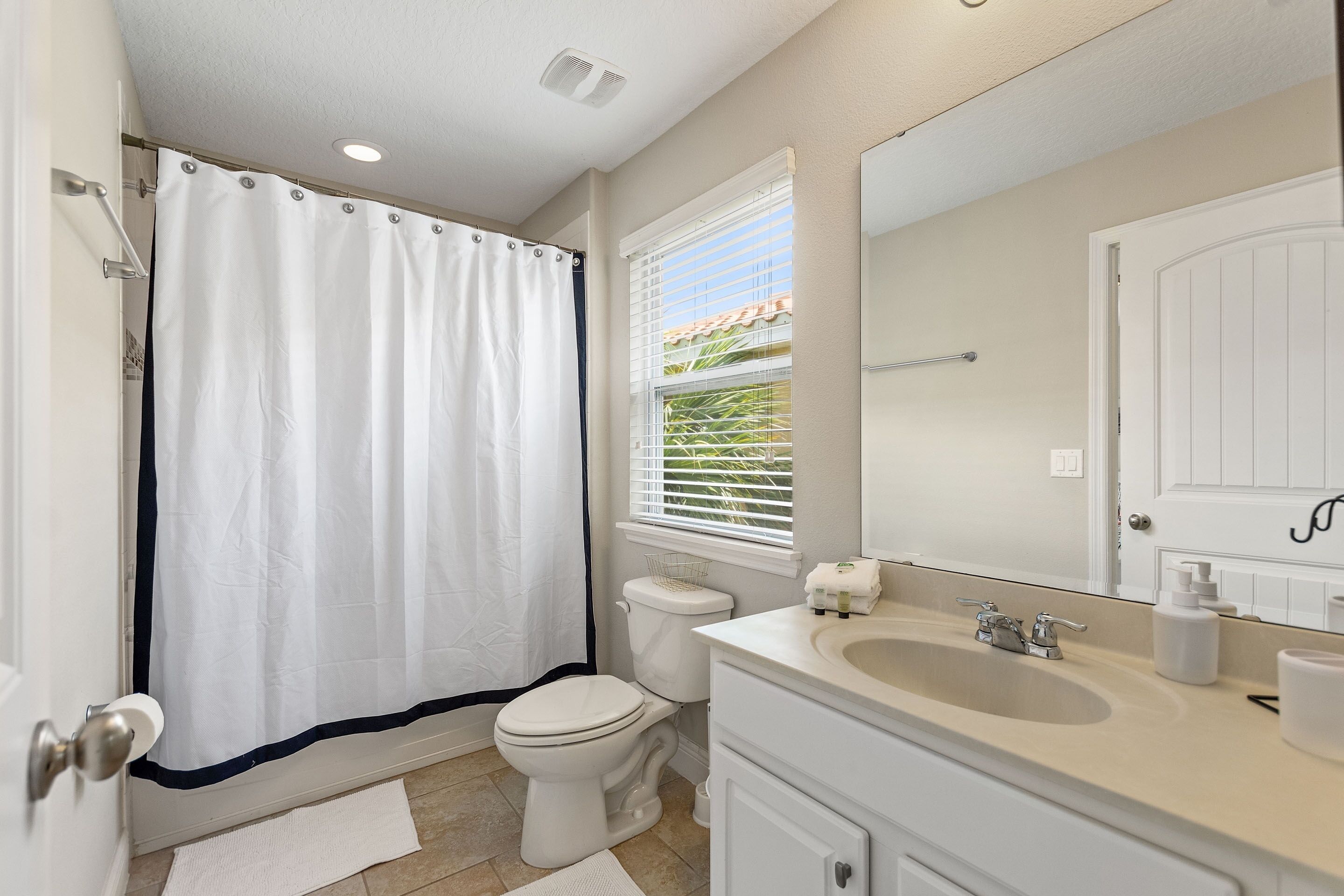 Une salle de bain avec des toilettes, un lavabo et un rideau de douche.