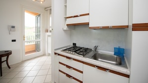 A kitchen with white cabinets, a gas stove, and a sink. - Casa della Rocca (Manerba del Garda)