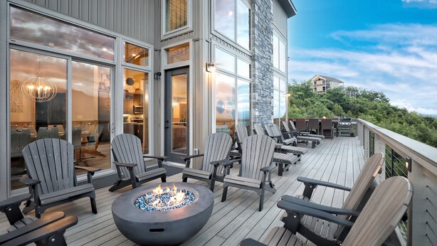 A deck with Adirondack chairs, a fire pit, and a view of a mountain.