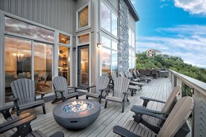 Una terraza con sillas Adirondack, un pozo de fuego y vistas a la montaña.