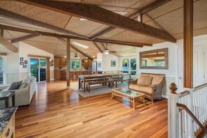 A spacious living area with hardwood floors, a dining table, sofas, and a staircase.