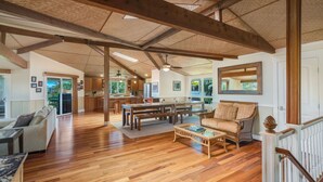 A spacious living area with hardwood floors, a dining table, sofas, and a staircase. - Lola Hale, Spacious Upgraded Hawaiiana House, A/C and Hot Tub (Princeville)