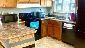 A kitchen with wooden cabinets, a granite countertop, a stove, a microwave, a dishwasher, and a refrigerator. - Wyoming Prairie Place (Gillette)