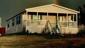 A two-story house with a porch and a staircase leading to the entrance. - Wyoming Prairie Place (Gillette)