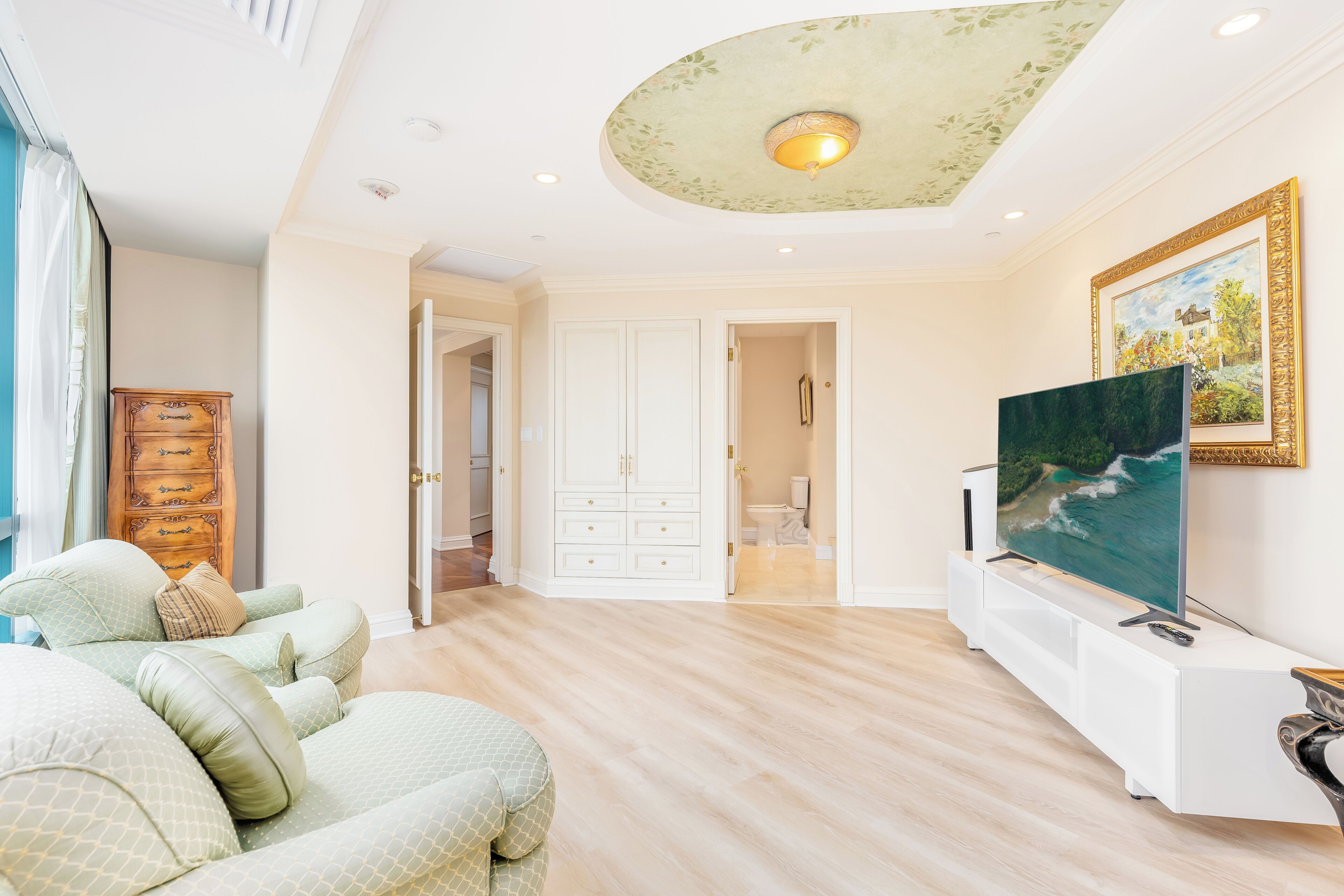 A spacious living room with a flat-screen TV, a sofa, and a cabinet.