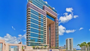 A high-rise hotel with a modern design, featuring a central atrium and a pool area.