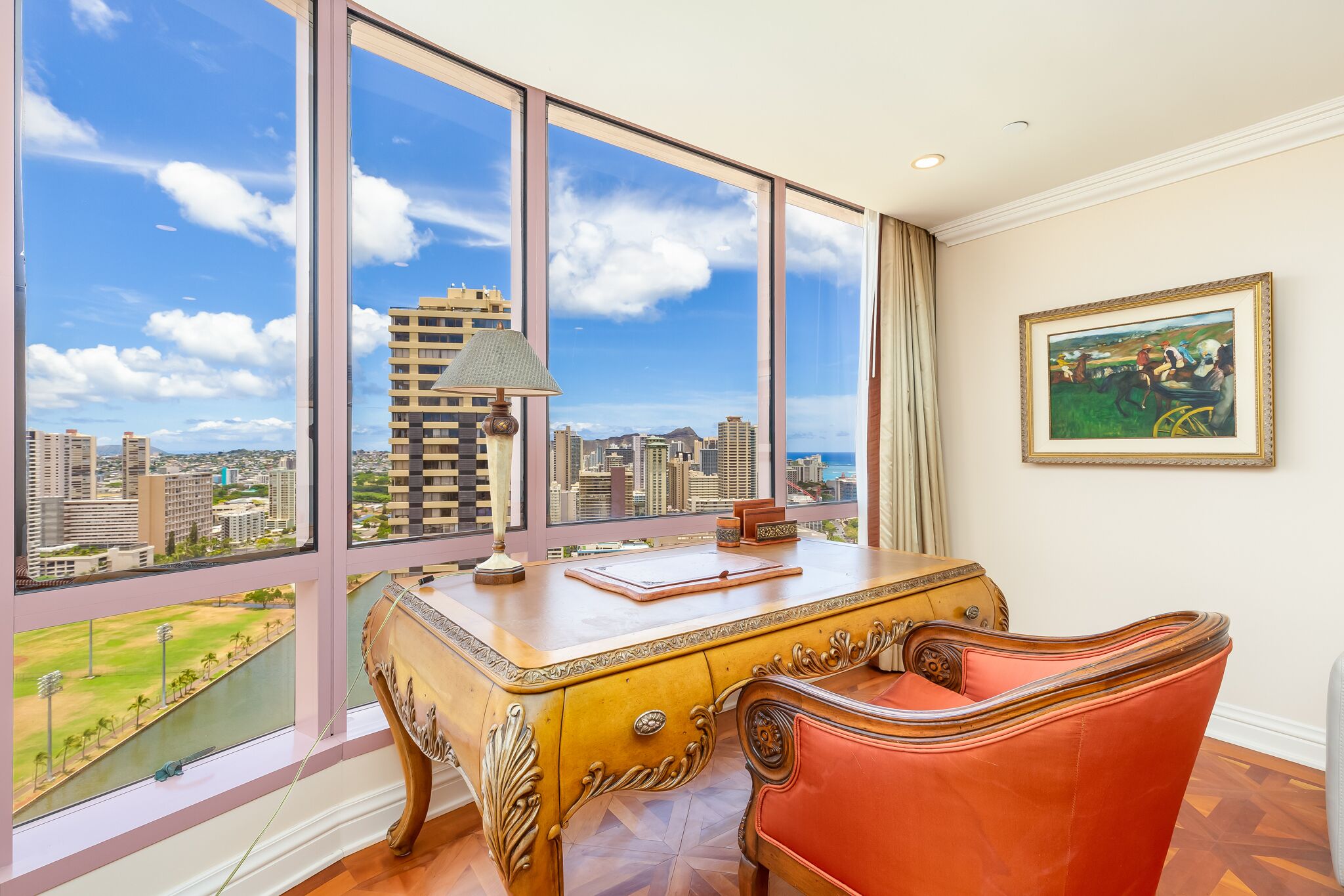 A room with a large window, a desk, a chair, and a painting.