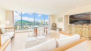 A spacious living room with a large window, a dining area, and a TV.