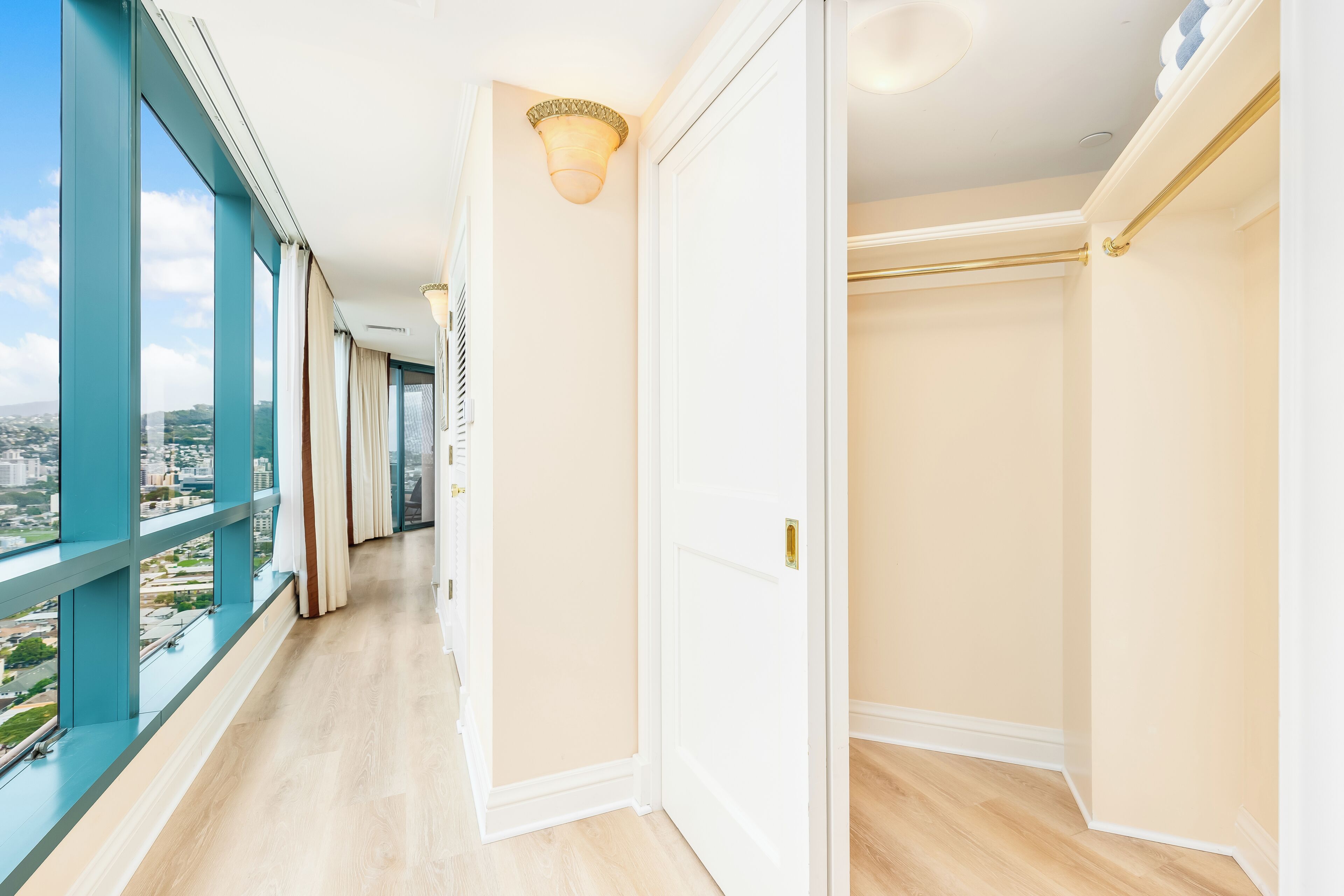 A corridor with a view of the city, a door, and a light fixture.