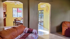 Una sala de estar con un sofá, una mesa de comedor con sillas y vistas al exterior.