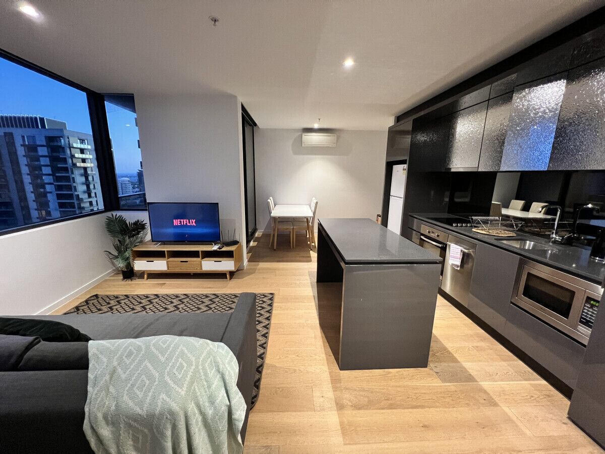 A modern apartment with a living room, dining area, and kitchen.