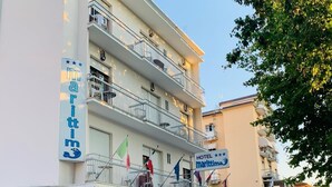 A multi-story hotel with balconies, a sign indicating it is a hotel, and a flag. - Hotel Marittima (Rimini)