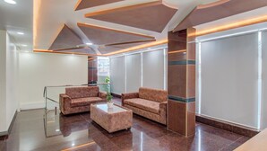 Un hall d’entrée moderne avec deux canapés, une table basse et une rambarde en verre.