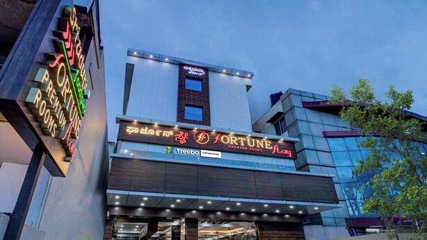 Un hôtel doté d’une façade moderne, d’une enseigne indiquant « CHAMBRES DE LUXE FORTUNE » et d’une entrée bien visible.