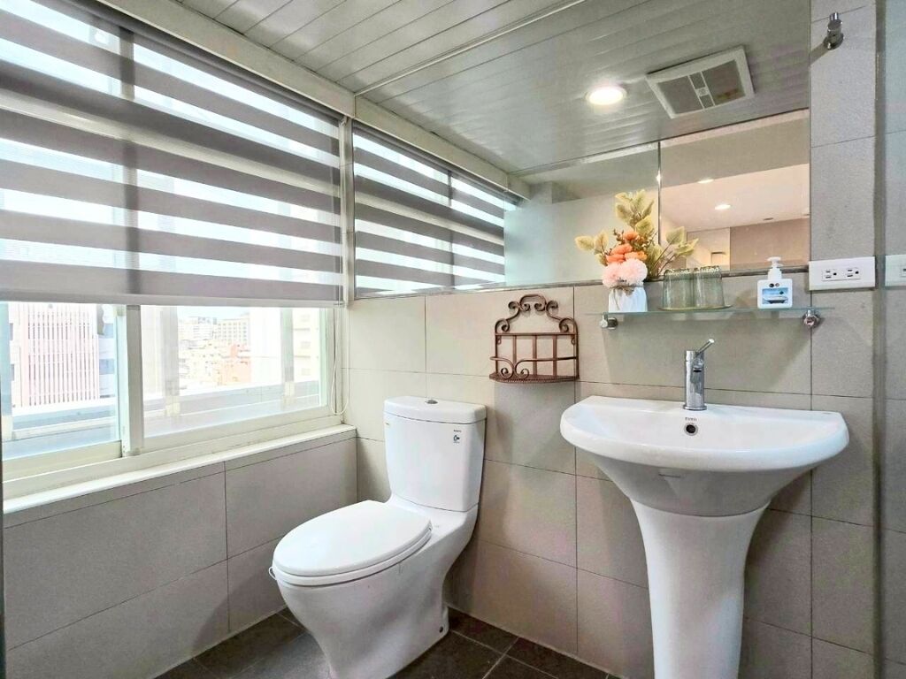 A bathroom with a toilet, sink, and window with blinds.