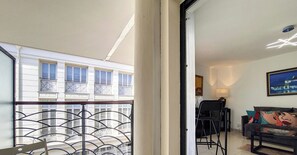 Ein Balkon mit Metallgeländer, einem Stuhl und einem Tisch.