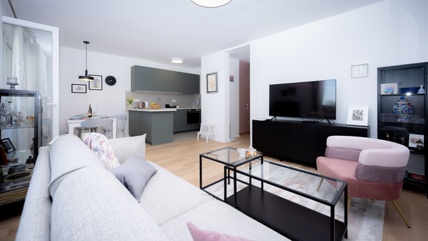 A modern living room with a sofa, a glass coffee table, a TV, and a kitchen area in the background. - Billie Holiday apartment with balcony (Split)
