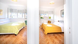 A room with two beds, wooden flooring, and large windows. - Billie Holiday apartment with balcony (Split)