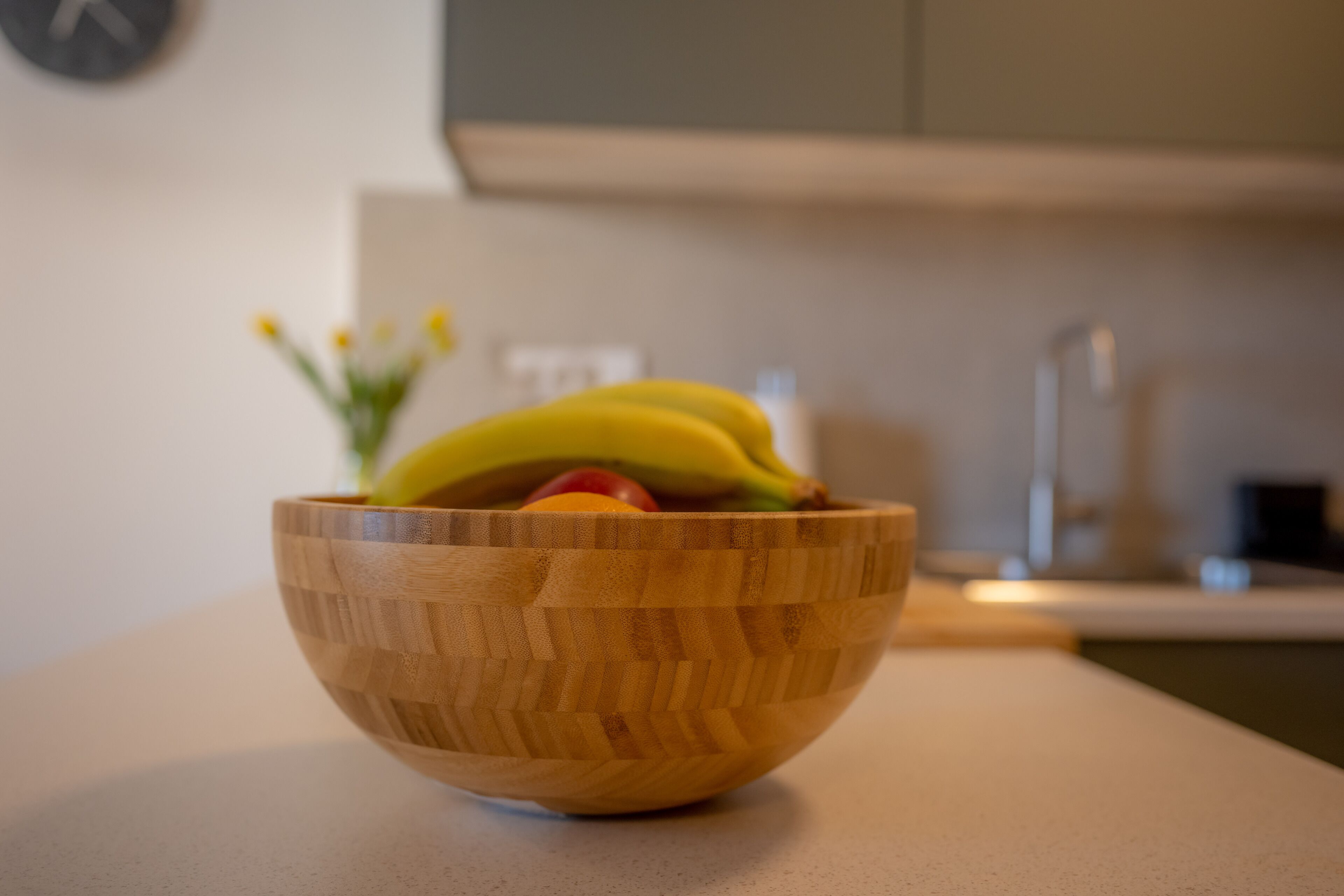 Un tazón de madera con frutas sobre una encimera de cocina.