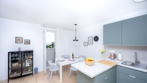 A modern kitchen with a white island, grey cabinets, and a dining area with a white table and chairs. - Billie Holiday apartment with balcony (Split)