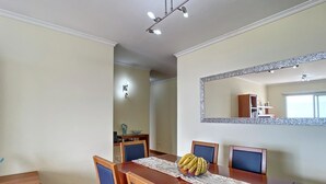 Un coin repas avec une table en bois, des chaises bleues et un miroir au mur.