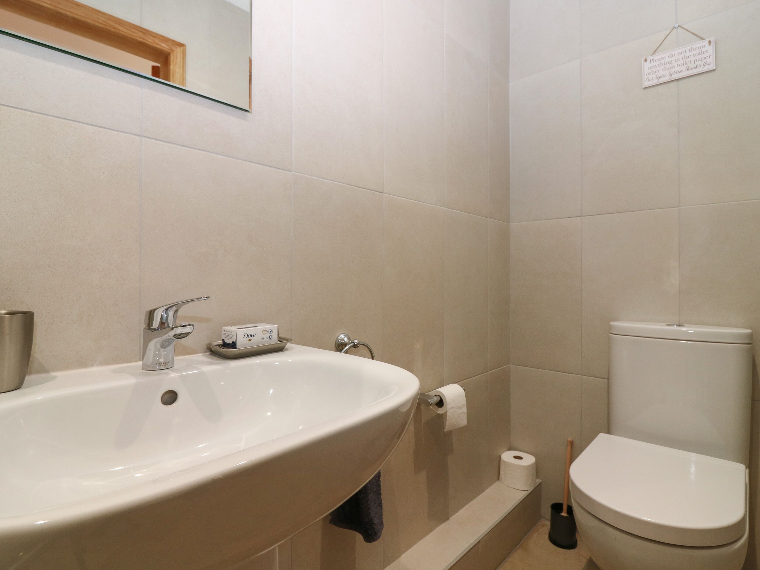 A bathroom with a sink, toilet, and a sign on the wall.