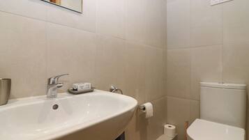 A bathroom with a sink, toilet, and a sign on the wall.