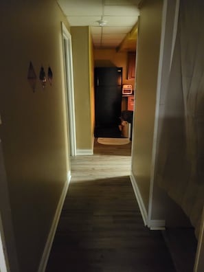 Enter a cozy hallway leading to a fully equipped kitchen with a countertop and appliances.