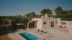 Un edificio de piedra con piscina, zona de estar exterior y pérgola.