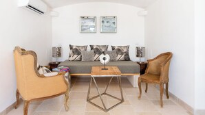 Una sala de estar acogedora con un sofá, dos sillones, una mesa de centro y una mesita de noche con una lámpara.