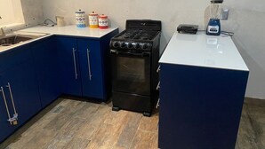 Kompakti keittiö, jossa on siniset kaapit, musta liesi ja valkoinen työtaso.