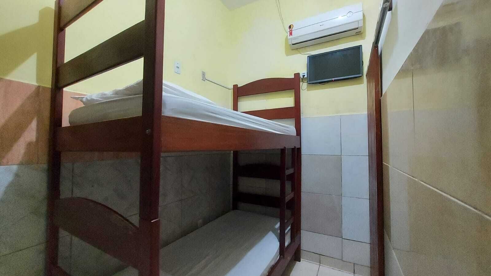 A bunk bed room with a television and air conditioning unit.
