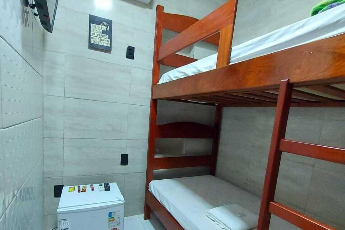 A small, compact room with a bunk bed, a small refrigerator, and an air conditioning unit.
