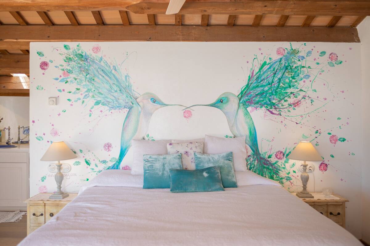 Un dormitorio con una cama grande, dos mesitas de noche y un mural en la pared.