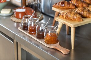 En morgenmadsanretning med croissanter og marmelade på en træplade.