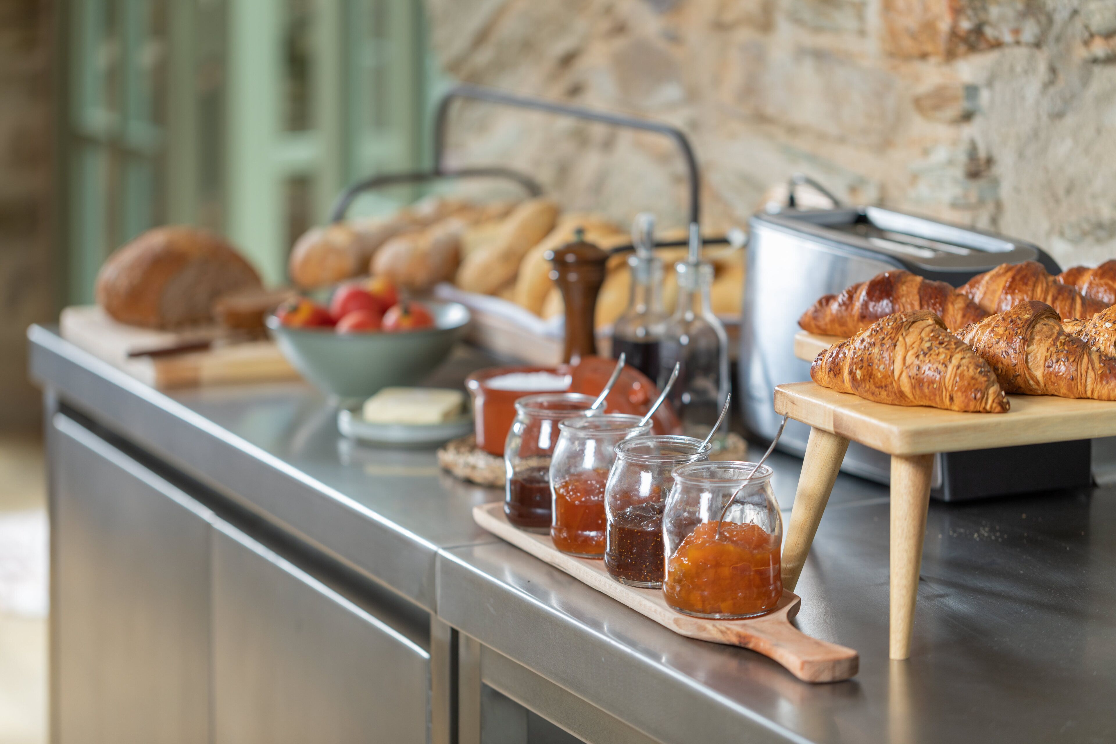 A breakfast buffet with various breads, pastries, and jams.