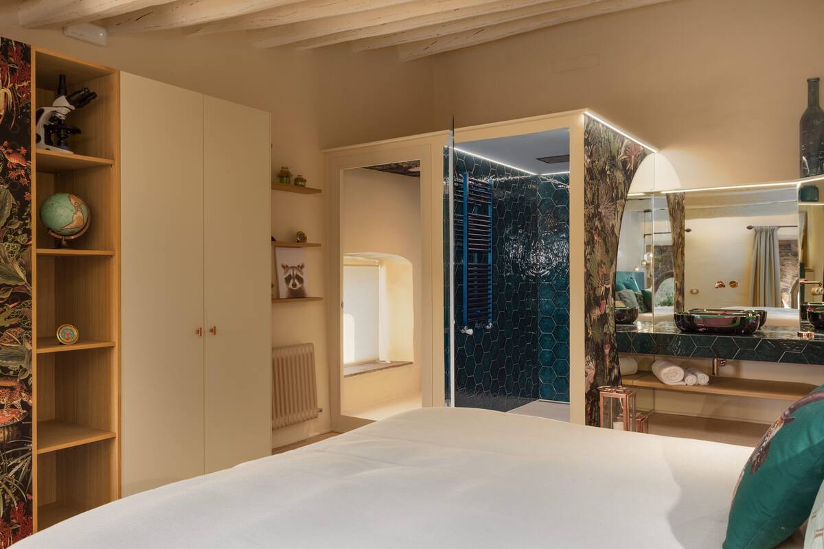 Un dormitorio con una cama grande, un armario de madera, un globo terráqueo y un baño con espejo y lavamanos.