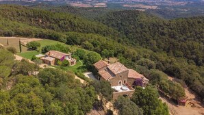Une propriété rurale comprenant une maison en pierre, un bâtiment plus petit et un espace clôturé où se trouvent des animaux.
