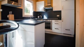A modern kitchen with white cabinets, a stainless steel oven, and a black countertop.