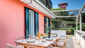 A dining area with a table set for six, surrounded by wicker chairs. - VILLA SCIROCCO - Brand New Waterfront Villa with Pool & Turkish Bath (Vico Equense)