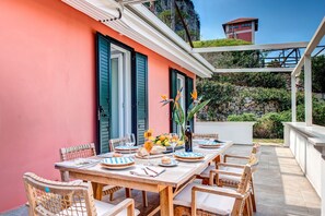 Enjoy meals al fresco in a shaded outdoor dining area surrounded by wicker chairs and a pergola.