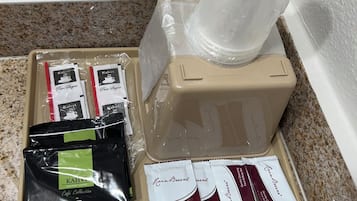 Una cafetera, un portacapsulas de café y un juego de cápsulas en una encimera de cocina.