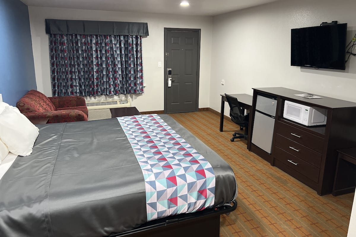 Ein Hotelzimmer mit Bett, Schreibtisch, Fernseher und Mikrowelle.