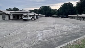 Un estacionamiento amplio con varios edificios, incluyendo un motel con múltiples habitaciones y una construcción pequeña con un área cubierta.