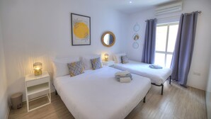 Hotelkamer met twee bedden, een nachtkastje met lamp, een spiegel aan de muur en een raam met gordijnen.