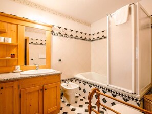 Ein Badezimmer mit einem Holzkosmetikschrank, einem Waschbecken, einem Bidet und einer Badewanne.