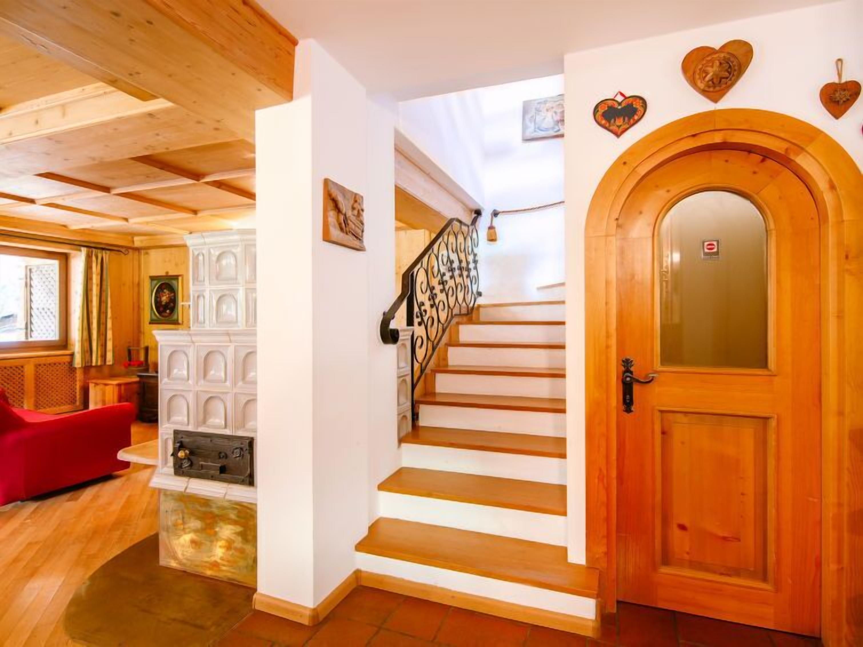 A wooden interior with a staircase, a red chair, and a door with a glass panel.